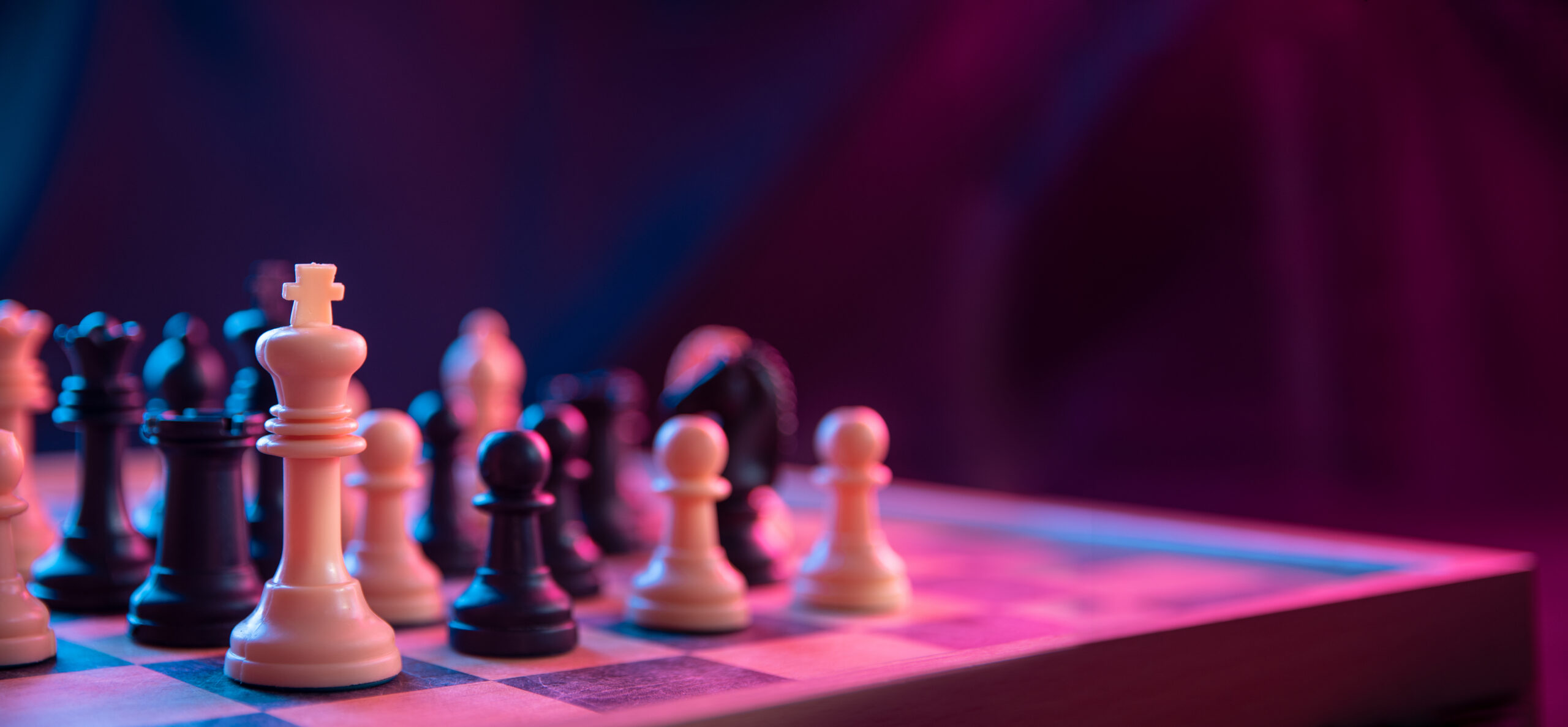 Chess pieces on a chessboard on a dark background shot in neon pink-blue colors. The figure of a chess .Close up. Positional